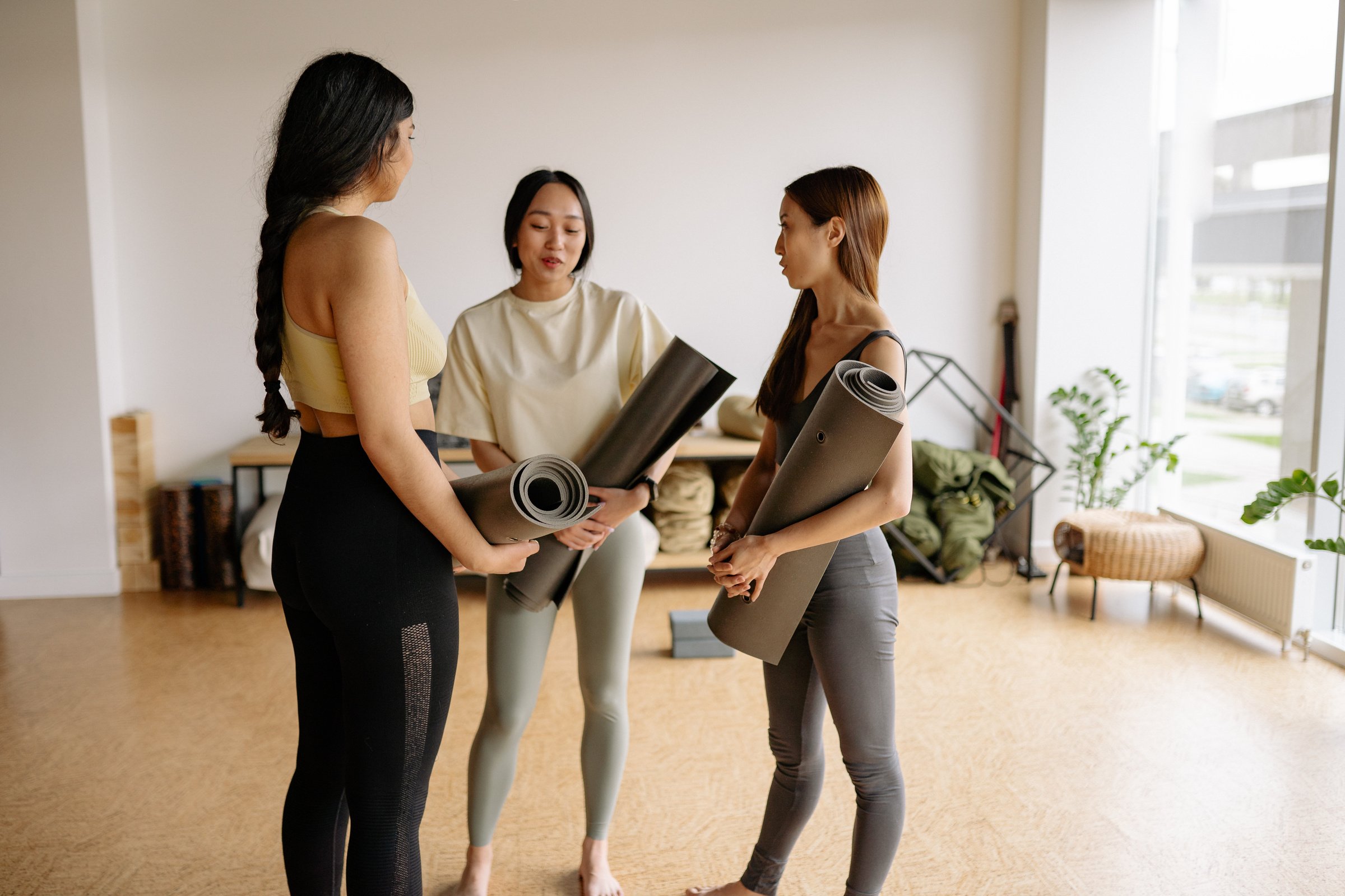 Women Holding Yoga Mats in a Studio